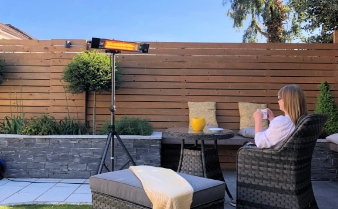 Woman sitting by an outdoor heater in a garden