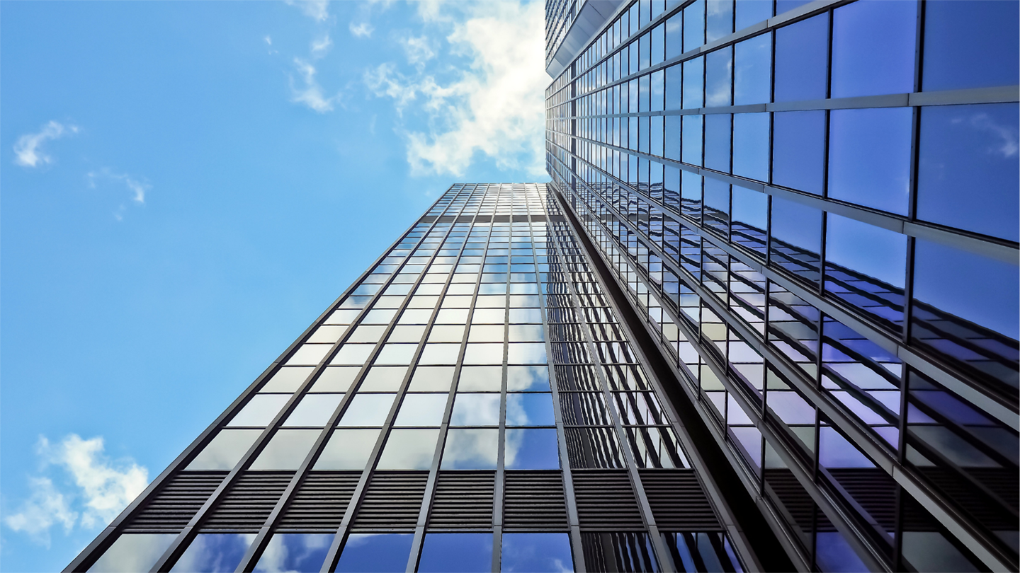 A skyscraper reflecting sunlight with clouds and sky above