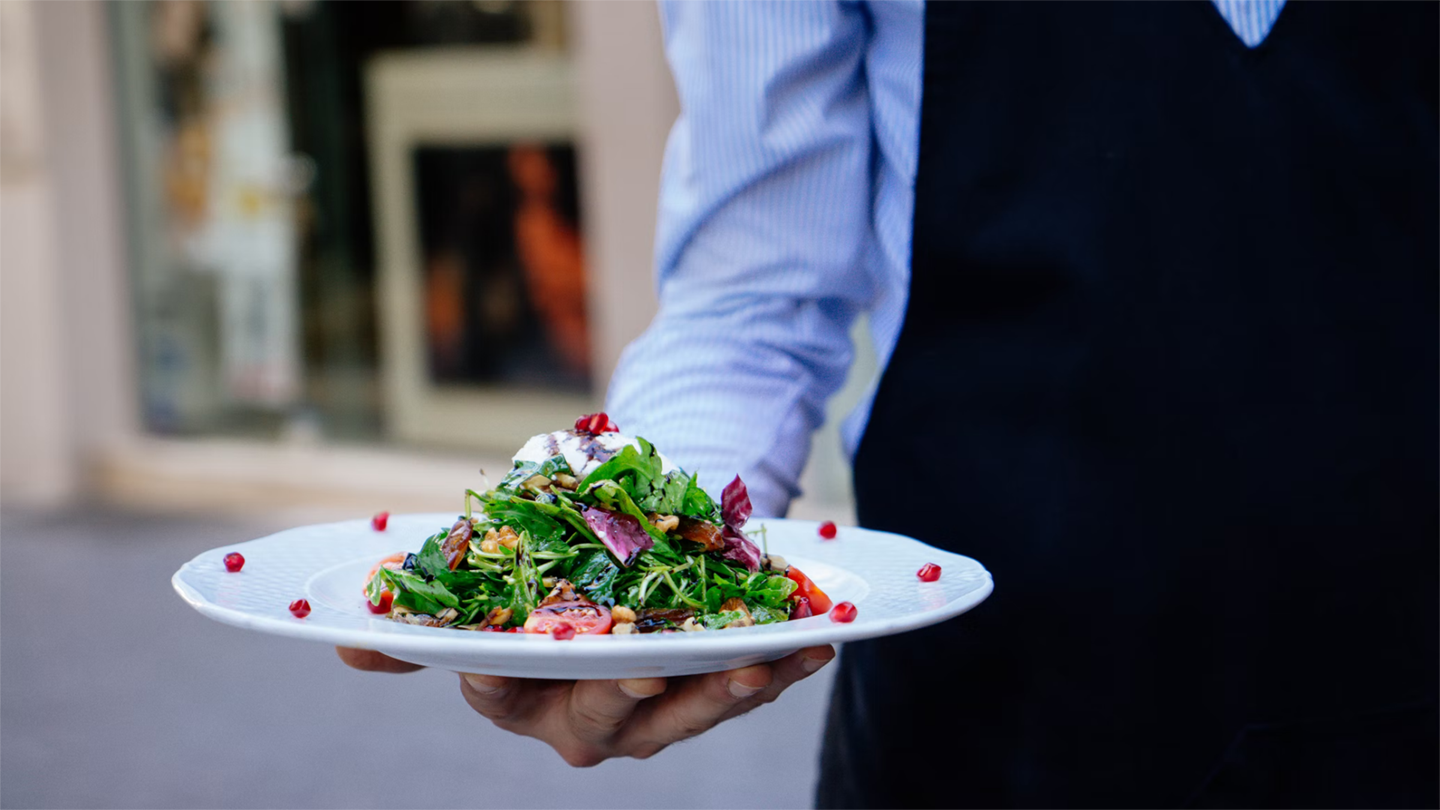 A waiter in a blue shirt holding a plate of dessert