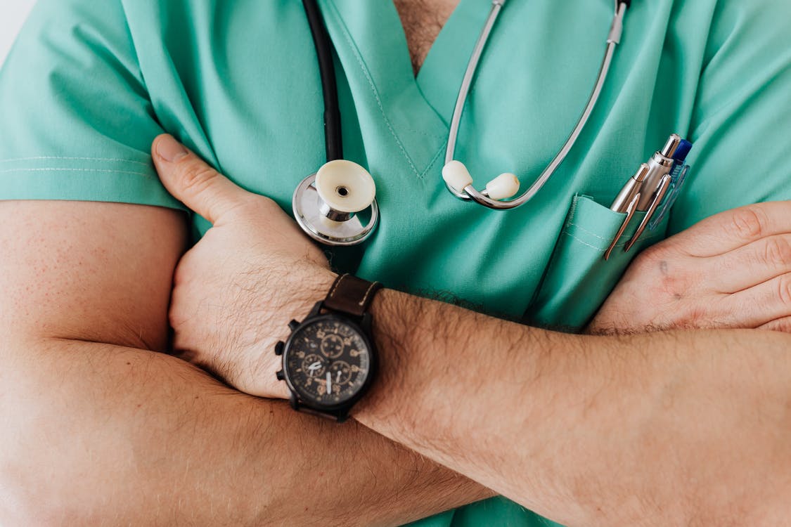 A doctor wearing scrubs folding his arms